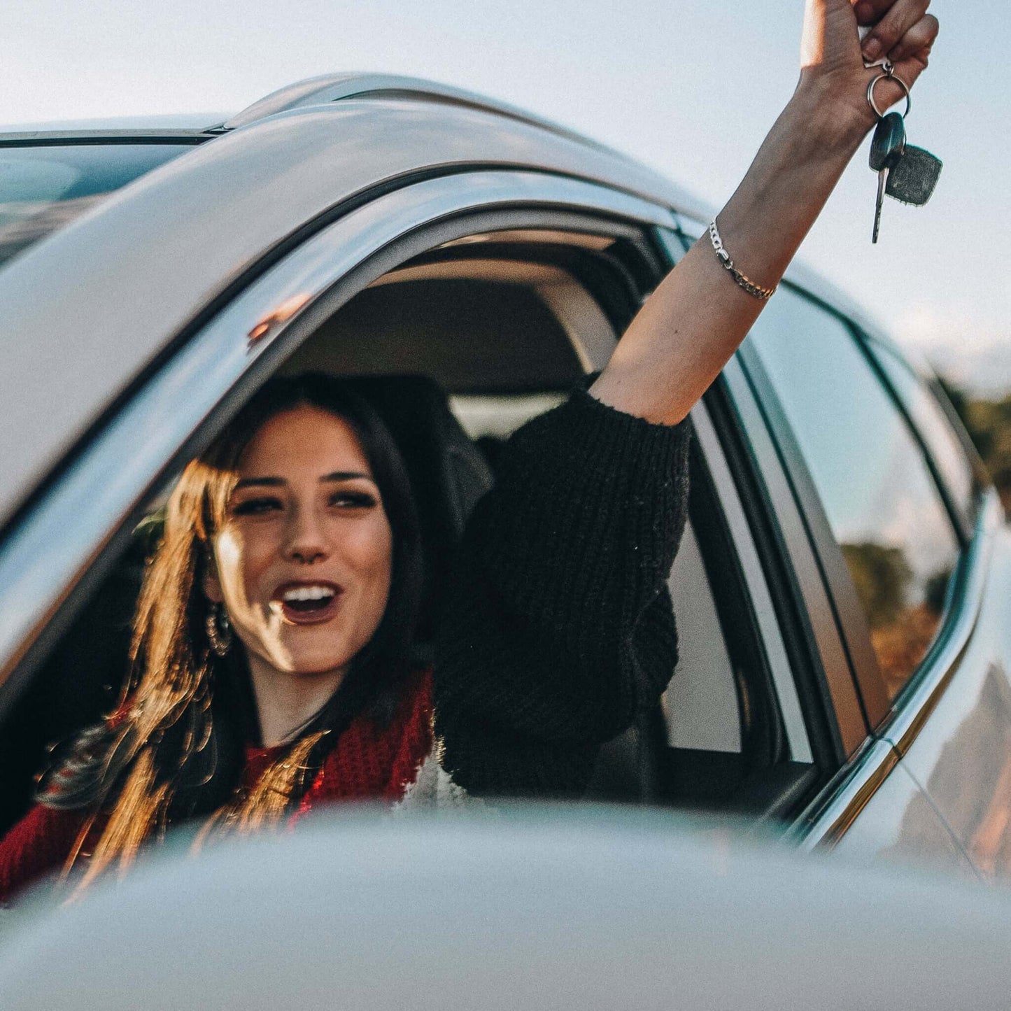 Have your driver's license translated: A young woman sits at the wheel and is happy about her driver's license